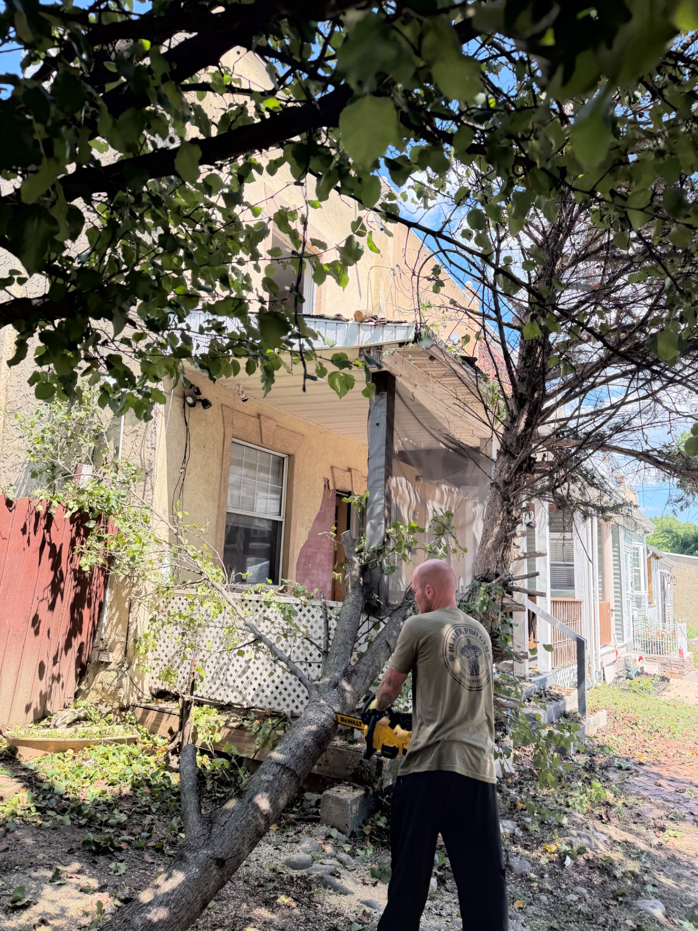 B.L.O.O.M. Entity crew member cutting the tree trunk down with a chainsaw away from the porch